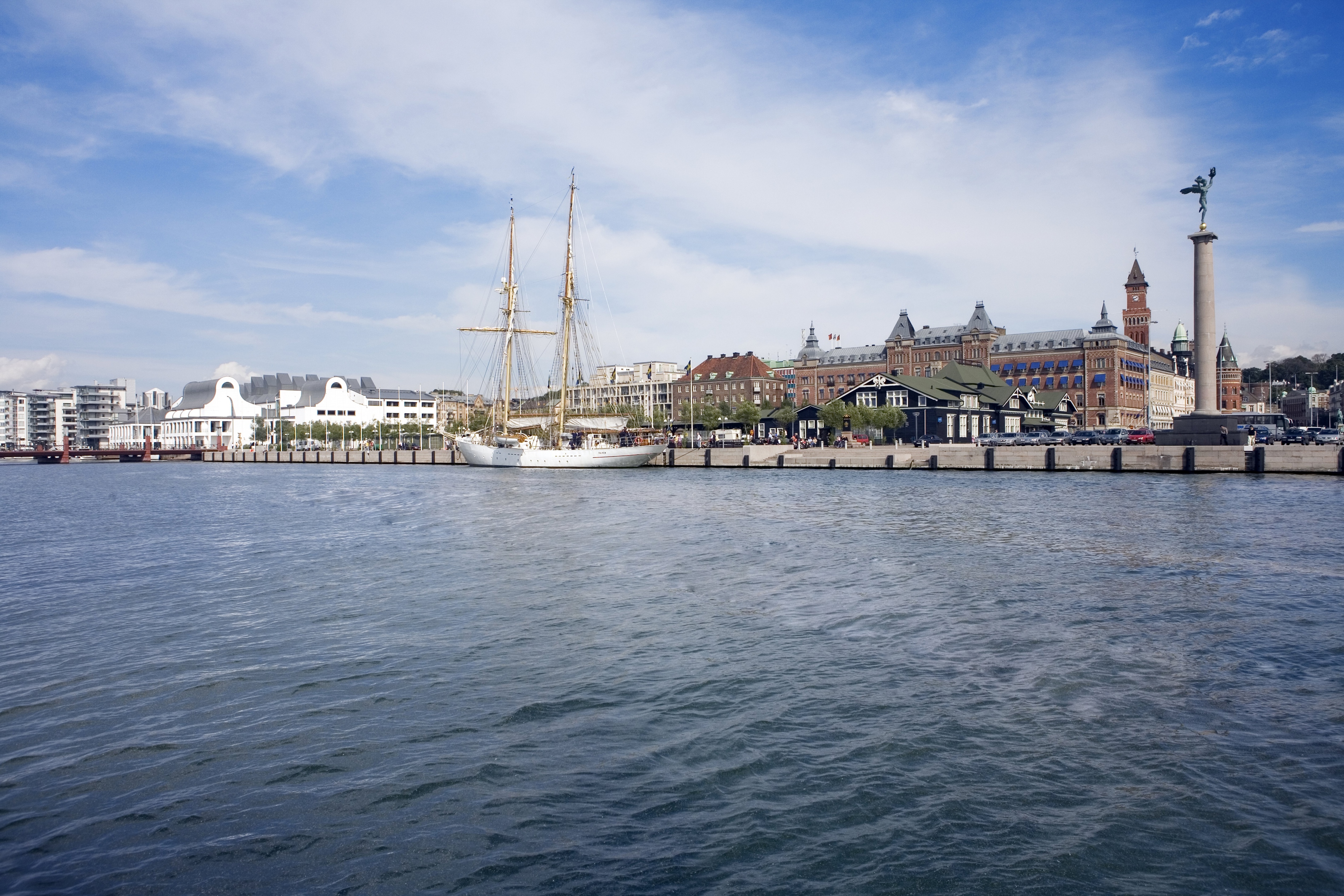 Sejlskib ved Helsingborg havn under klar blå himmel, med historiske bygninger i baggrunden.