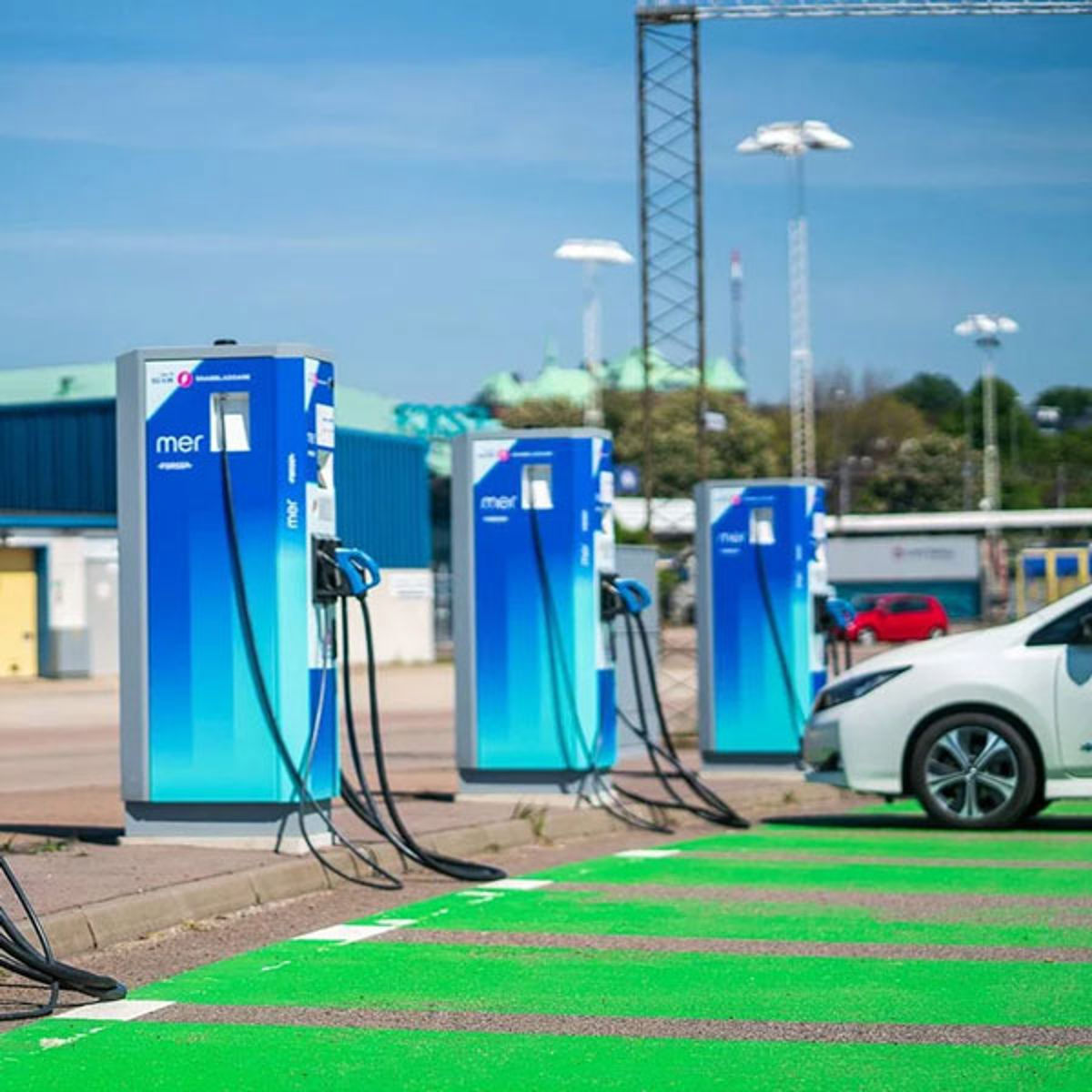 Electric car charger at station with blue and white charging points in daylight.