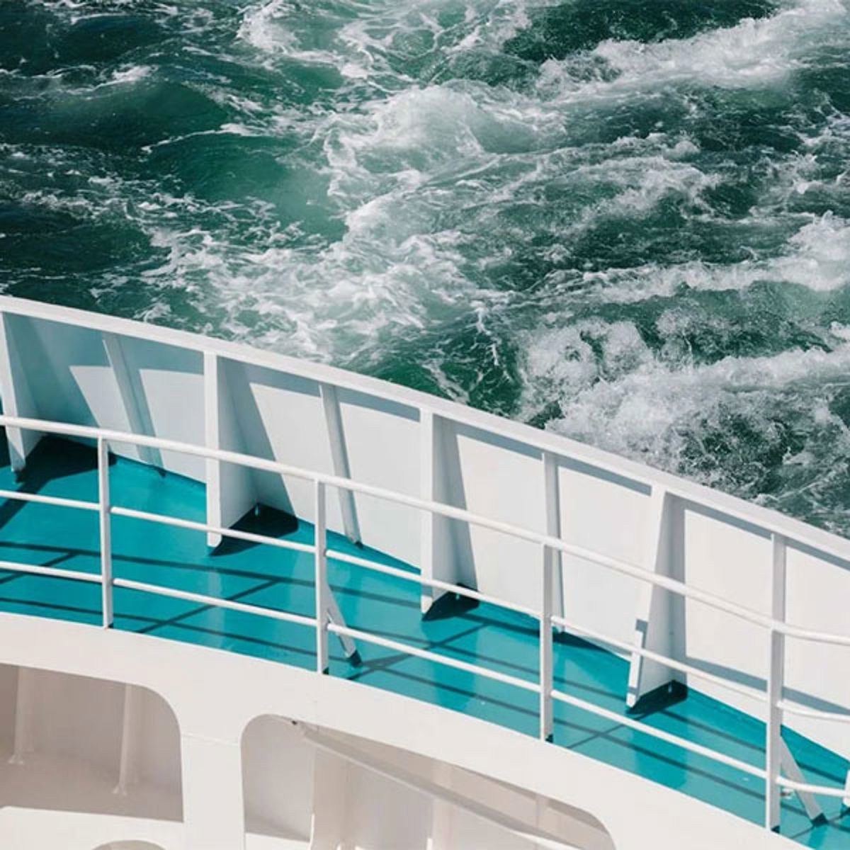 Turquoise Forsea Deck Green viewed from above with sea spray from waves hitting the ship's railing.