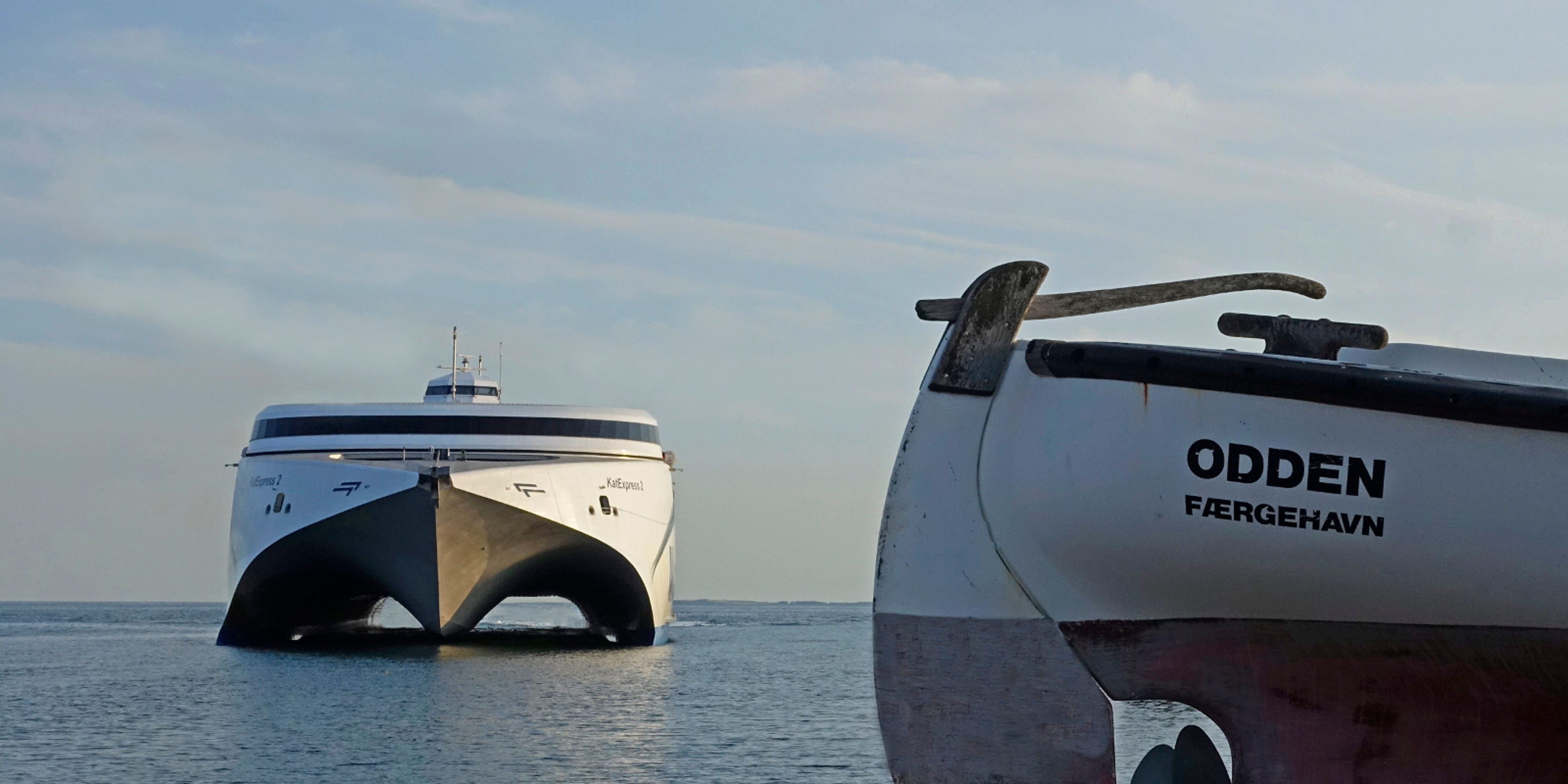 Molslinjen færge sejler ind mod Odden havn hvor der i forgrunden ses stevnen af en båd med "Odden" som navn.