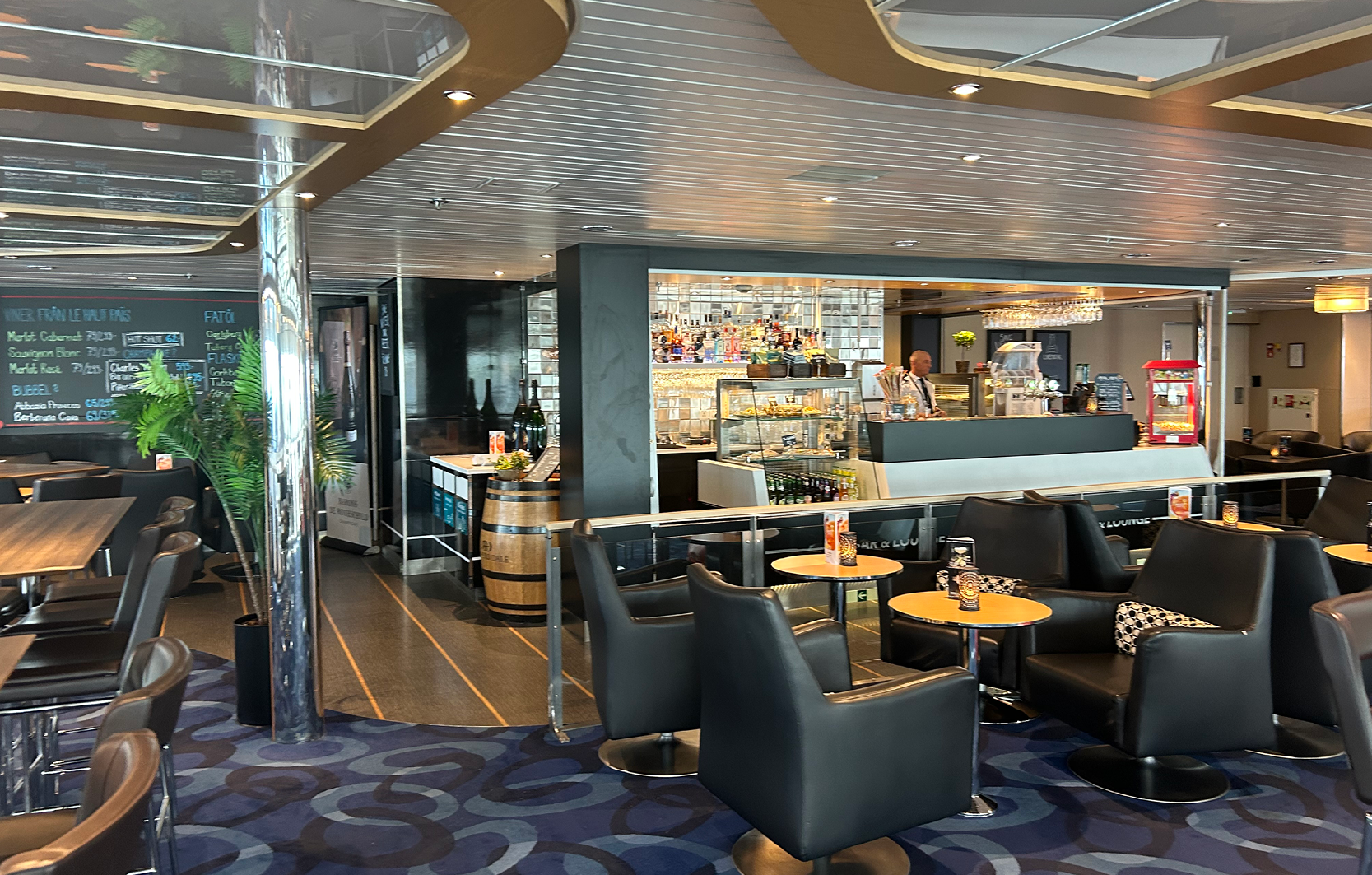 Café på Molslinjen-färja med komfortabla svarta läderstolar och bartender bakom välutrustad bardisk.