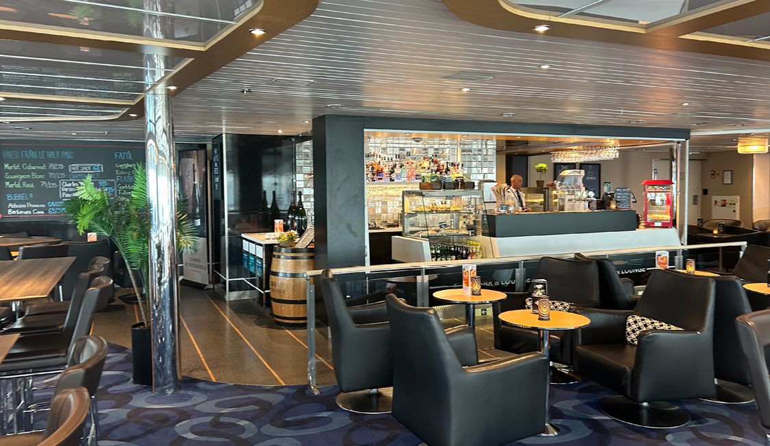 Café på Molslinjen-färja med komfortabla svarta läderstolar och bartender bakom välutrustad bardisk.