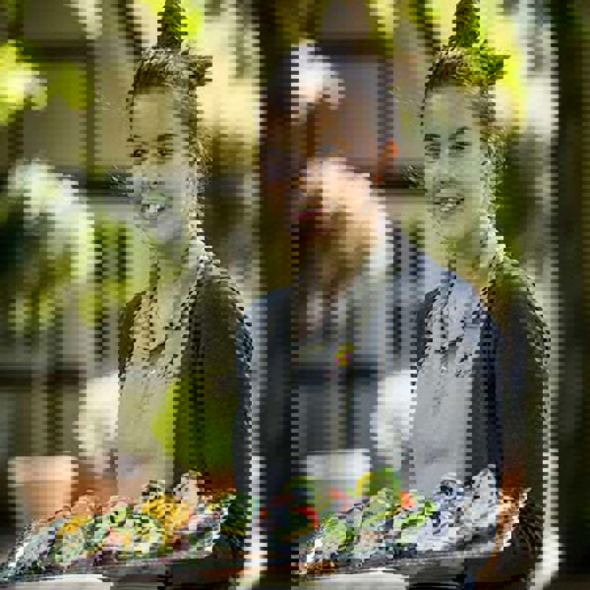 Servitris på Gavnø Slott ler och håller en smörrebröd på en bricka i handen.