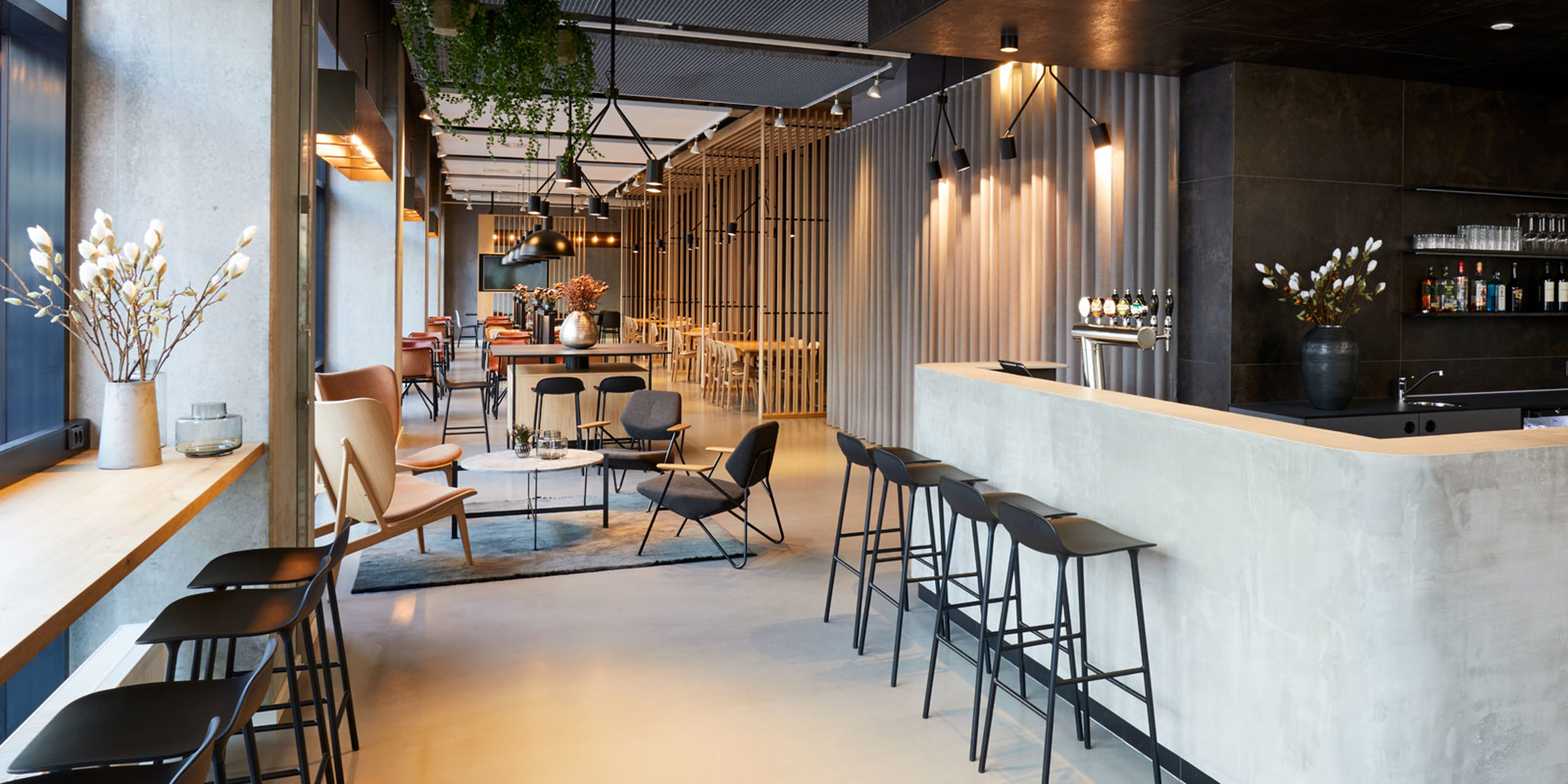 Modernt caféinteriör i Zleep Hotels Lounge med stilfull design, eleganta stolar och bord samt smakfullt barområde.