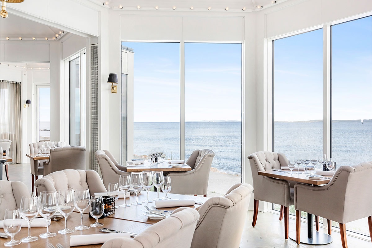 Utsikt över havet från Marienlyst från insidan av ett mycket ljust rum med bord och stolar i modern stil.