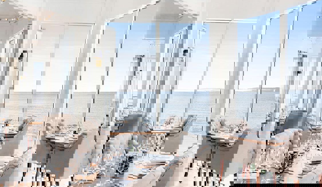 Utsikt över havet från Marienlyst från insidan av ett mycket ljust rum med bord och stolar i modern stil.