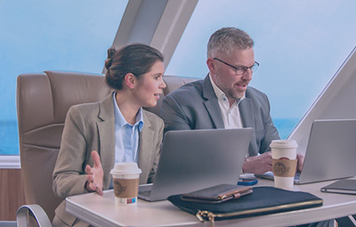 To personer der sidder og arbejder ved deres computer i Keepers business lounge ombord på Molslinjen