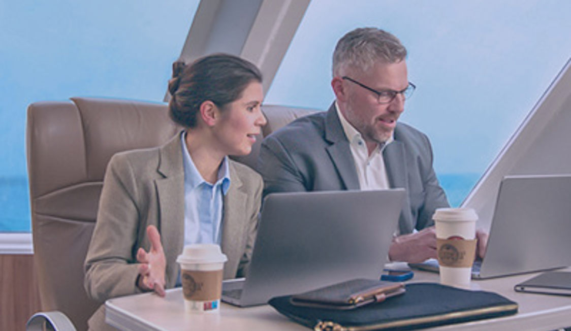 To personer der sidder og arbejder ved deres computer i Keepers business lounge ombord på Molslinjen