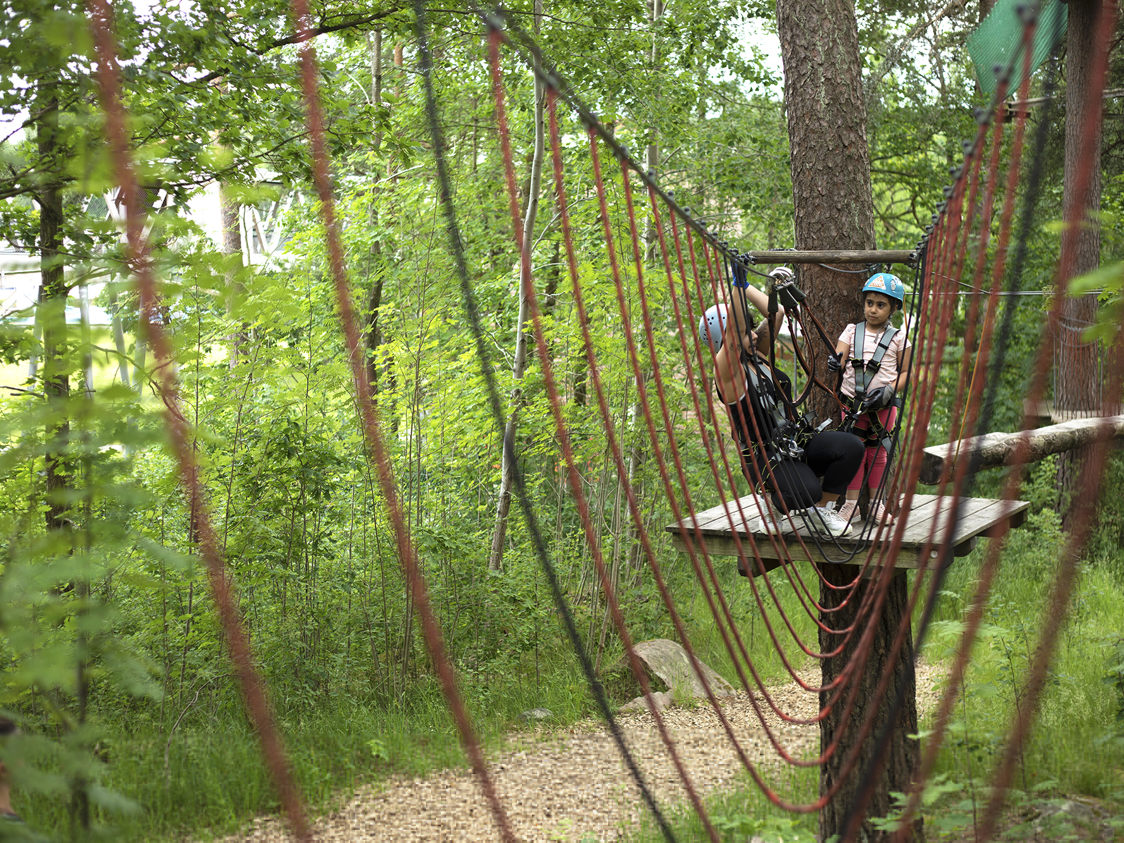 Upzone klatrestativ for børn med farverige klatregreb set fra siden i en udendørs legeplads.