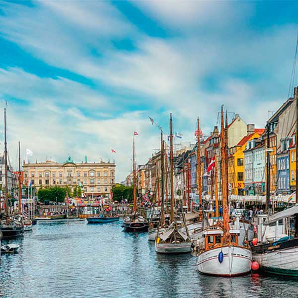 Sejlskibe i Nyhavn havn omkranset af farverige bygninger under blå himmel i København, Danmark.