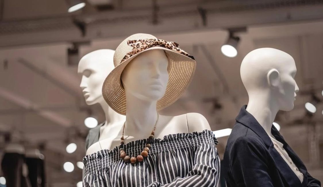 Shopping skyltdockor visar klädstil med randig topp och halmhatt i en butiksmiljö.