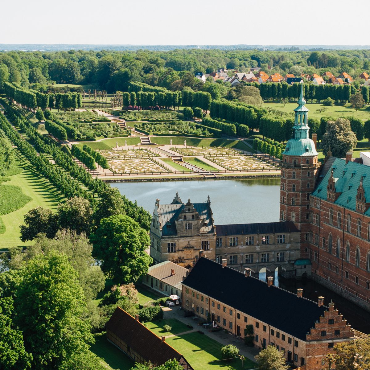 Luftfoto af Frederiksborg Slot med udsigt over den smukke have og omkringliggende grønne landskab.