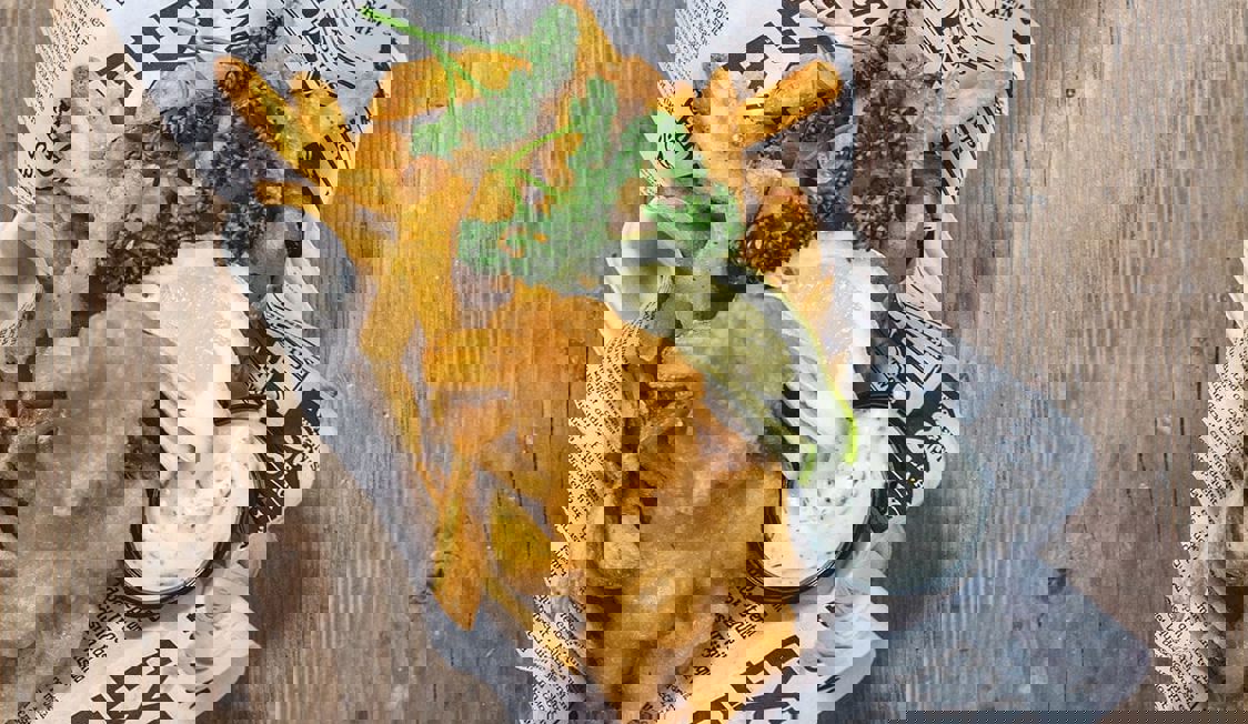 Närbild på fish n chips på ett träbord.