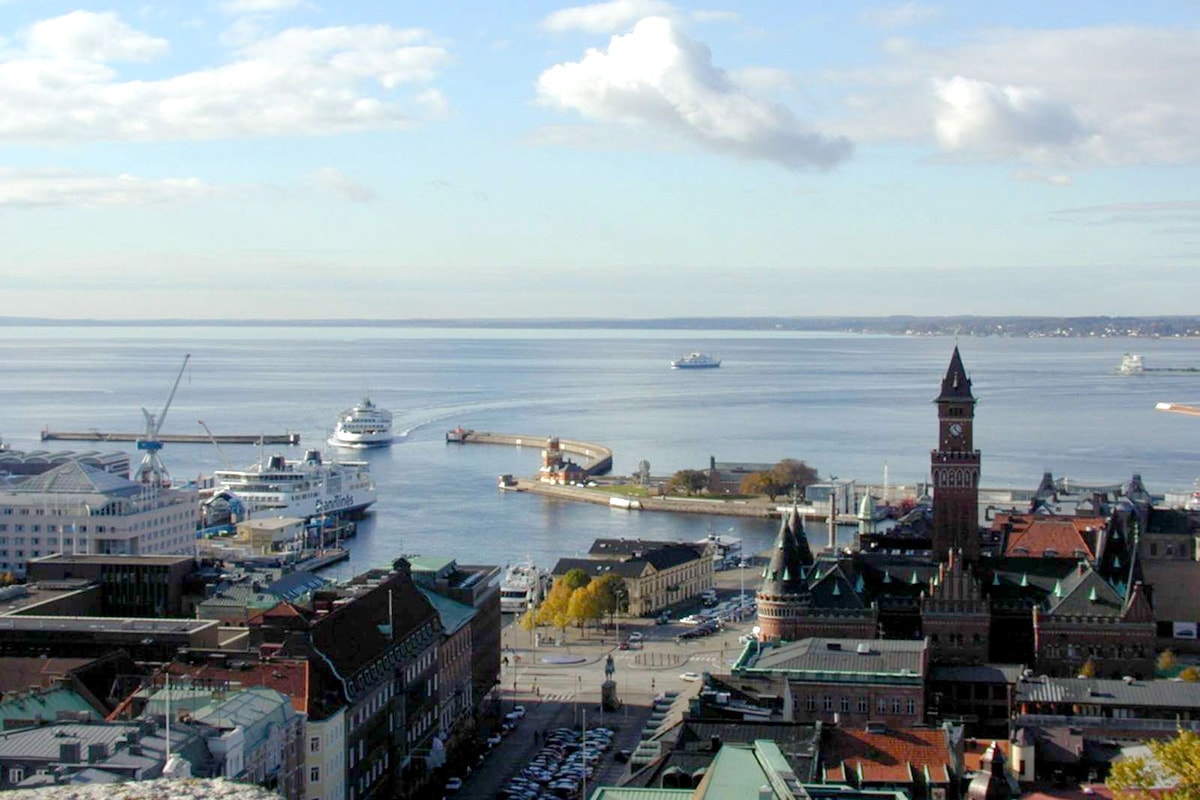 Helsingborg färja ses uppifrån segla över havet med stadens silhuett i bakgrunden.