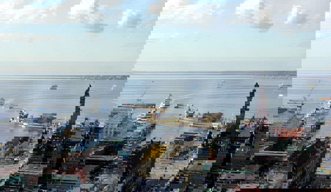 Helsingborg färja ses uppifrån segla över havet med stadens silhuett i bakgrunden.