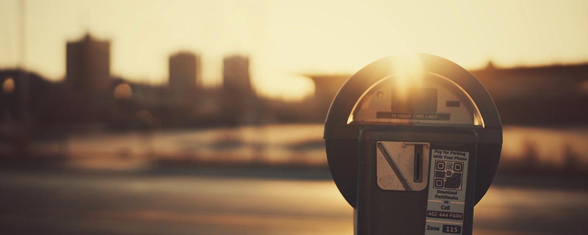 Närbild av en parkeringsautomat i solnedgångens ljus.