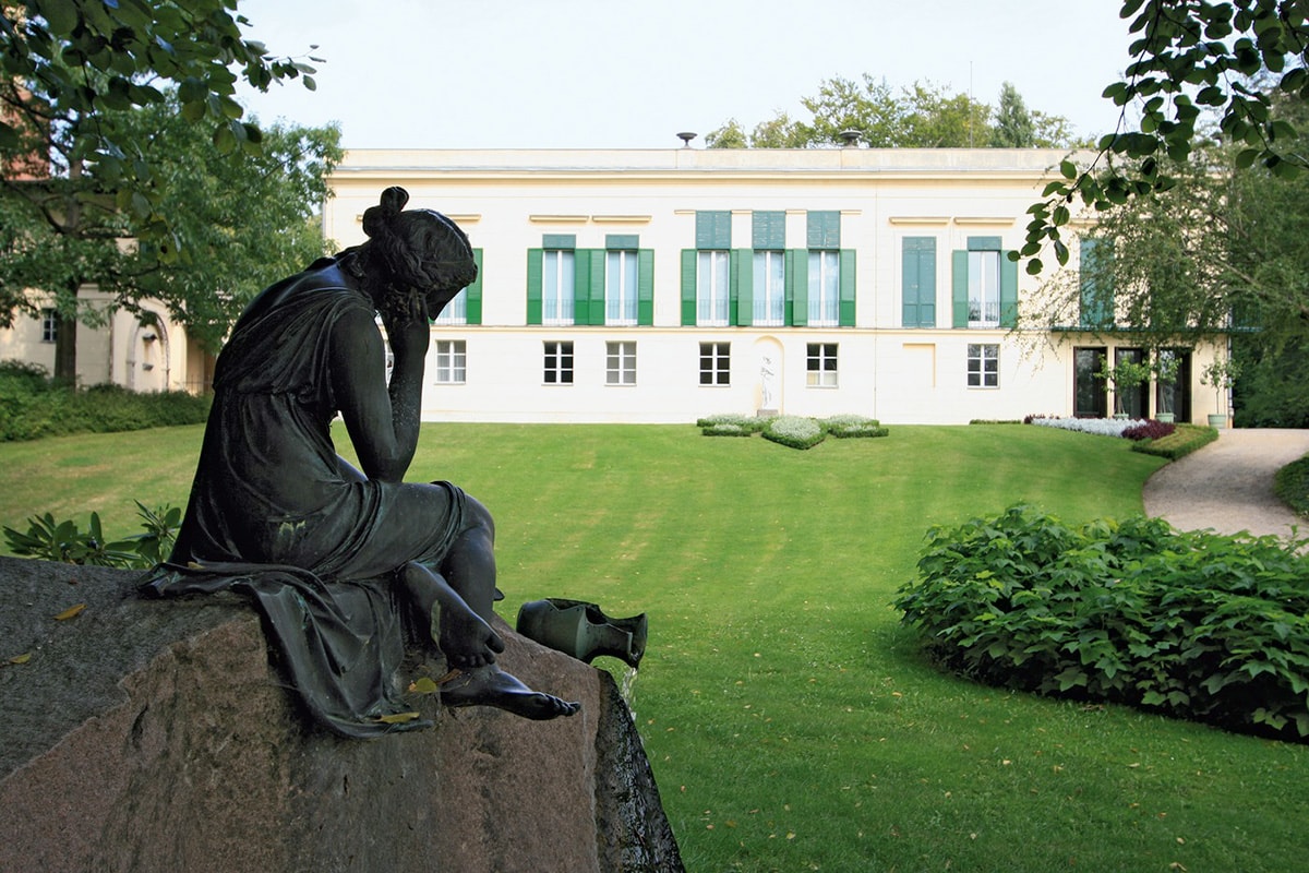 En staty står i förgrunden i en park i Berlin Potsdam.