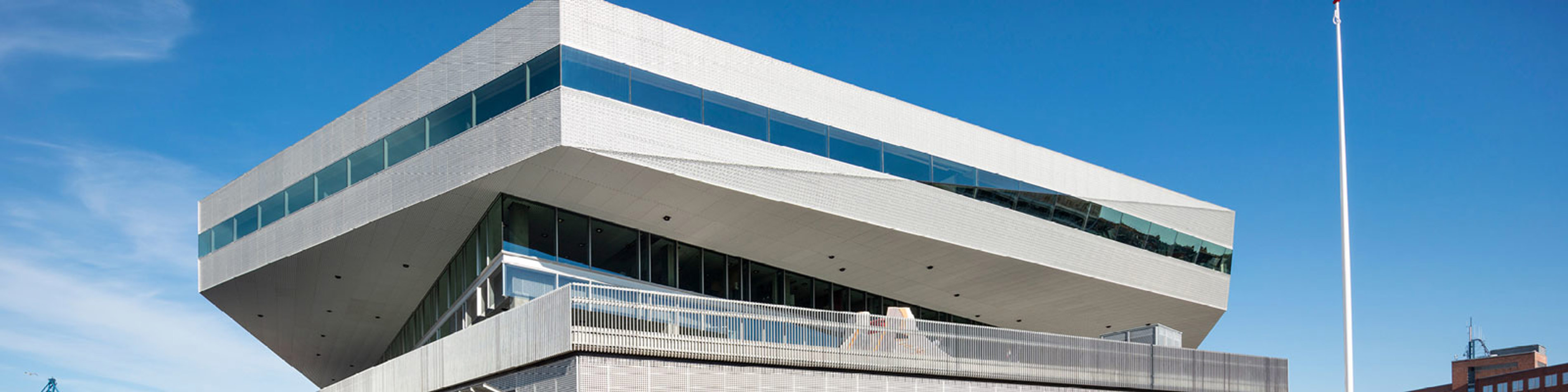 Dokk1 bibliotek i Aarhus med moderne arkitektur og glasfacader under en klar blå himmel.