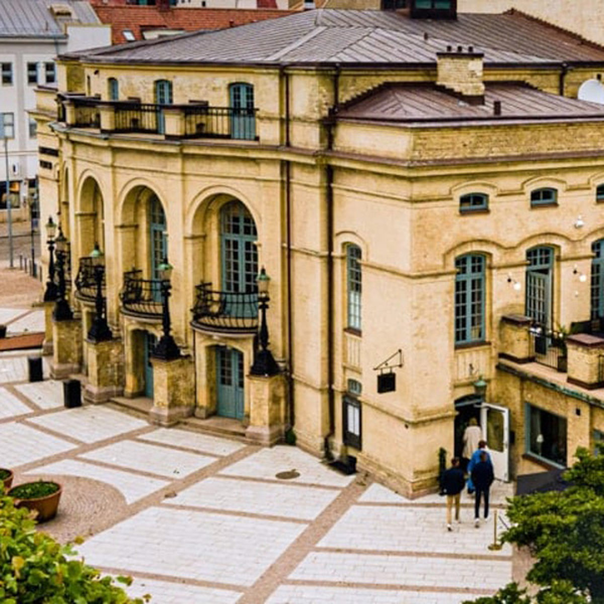 Historisk bygning med bueformede vinduer og smedejernsbalkoner set fra oven.