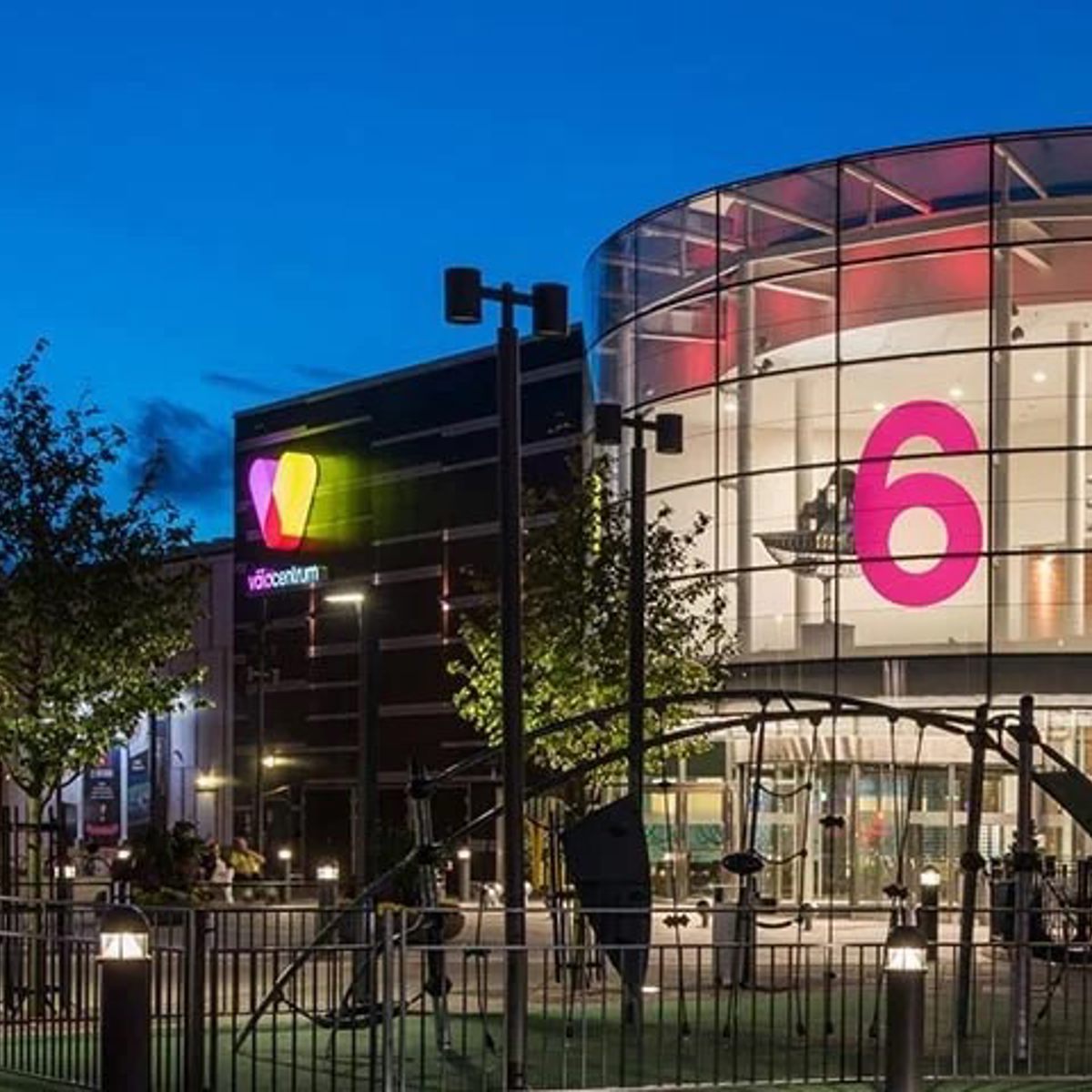 Kuppelformet biografindgang med stort pink 6-tal oplyst om natten ved Vejle biocenter.