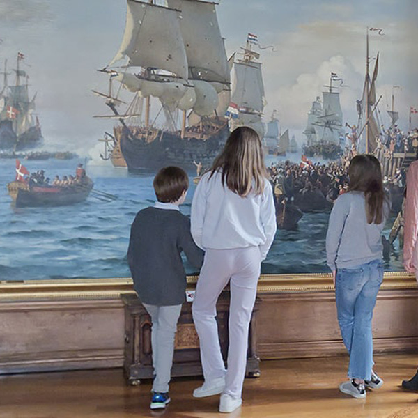 Familj betraktar tavla på Frederiksborgs slott med historisk sjöstridsscen.