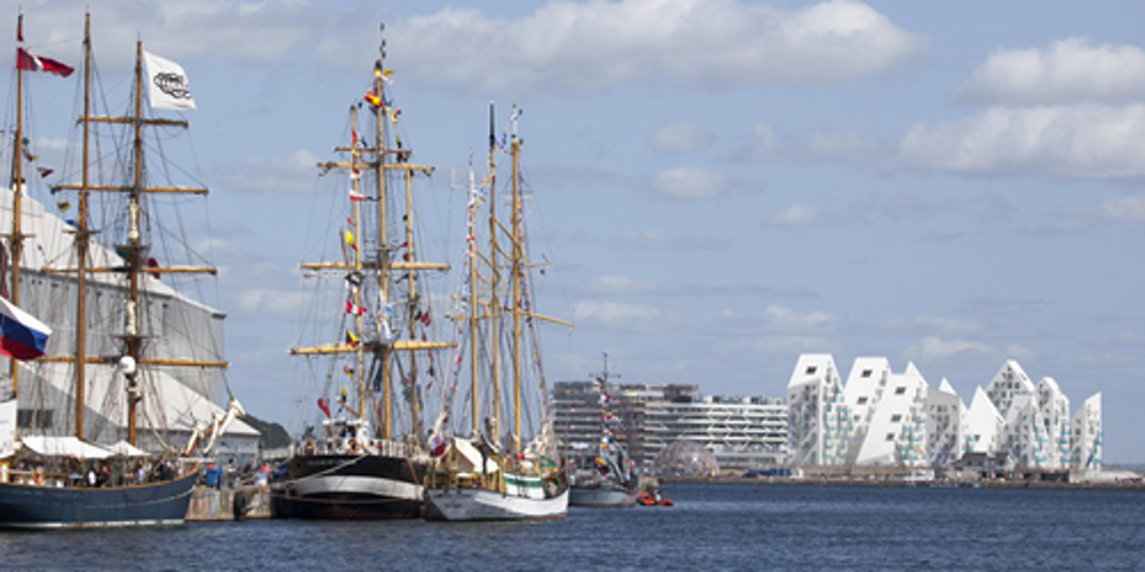 Sejlskibe langs kajen ved Aarhus havn med den moderne bygning Isbjerget som baggrund.