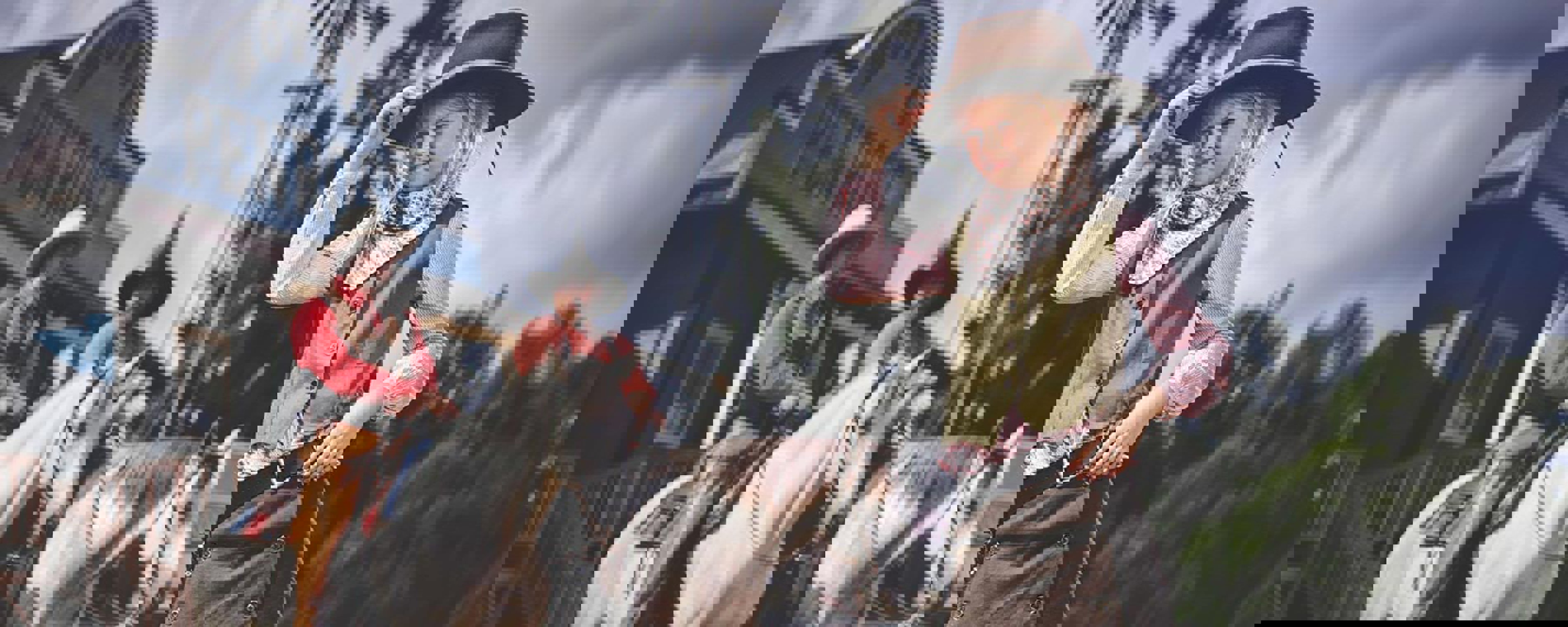 Et barn i cowboy udstyr og to mænd på heste ses i forgrunden af High Chaparral.