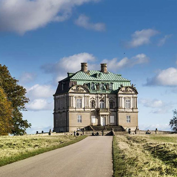 En stor och majestätisk byggnad syns i fjärran med en blå himmel med få moln.