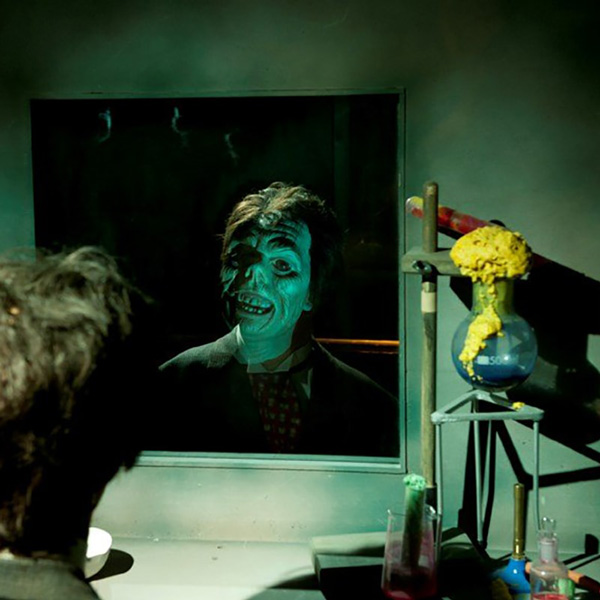 Mystic Exploratorie ansikte ser sig själv i spegeln med halvt monsteransikte i ett laboratorium.