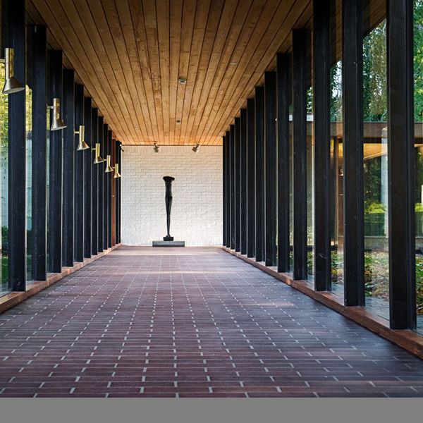 Den moderna Louisiana-statyetten på podium i elegant korridor med trägolv och taklampor.