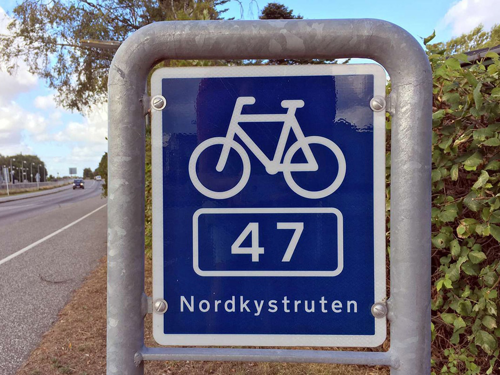 Cykelskylt för Nordkustleden rutt 47 i Nordsjælland med blå bakgrund, vit cykelsymbol och text.