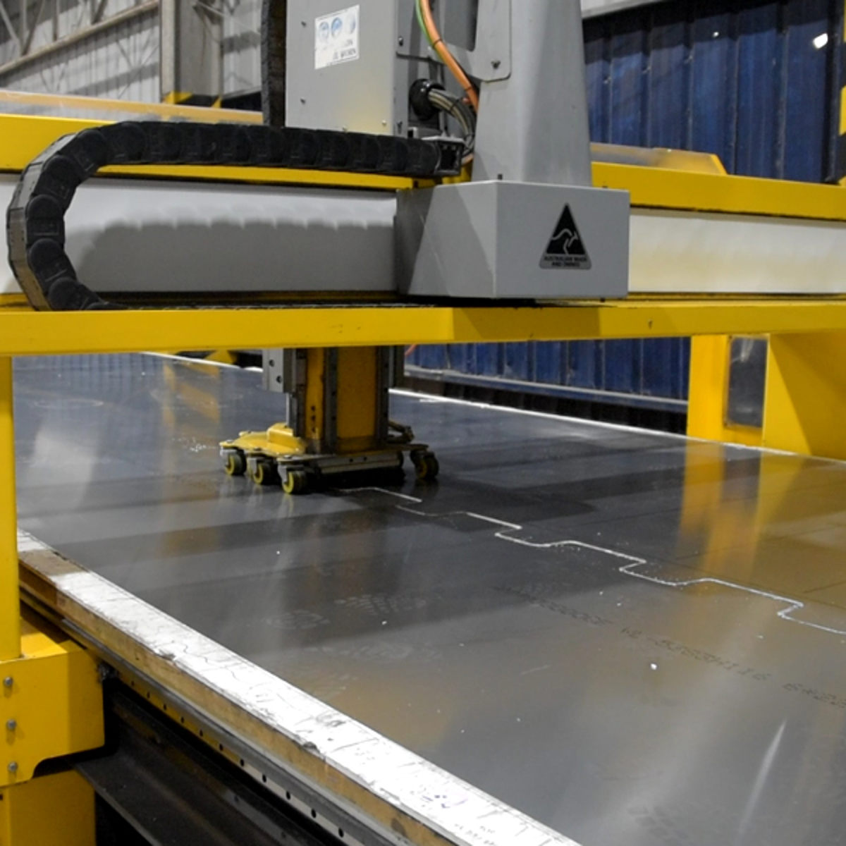 CNC-maskine skærer præcist i metalplade, fremhævet i en fabrikshal.