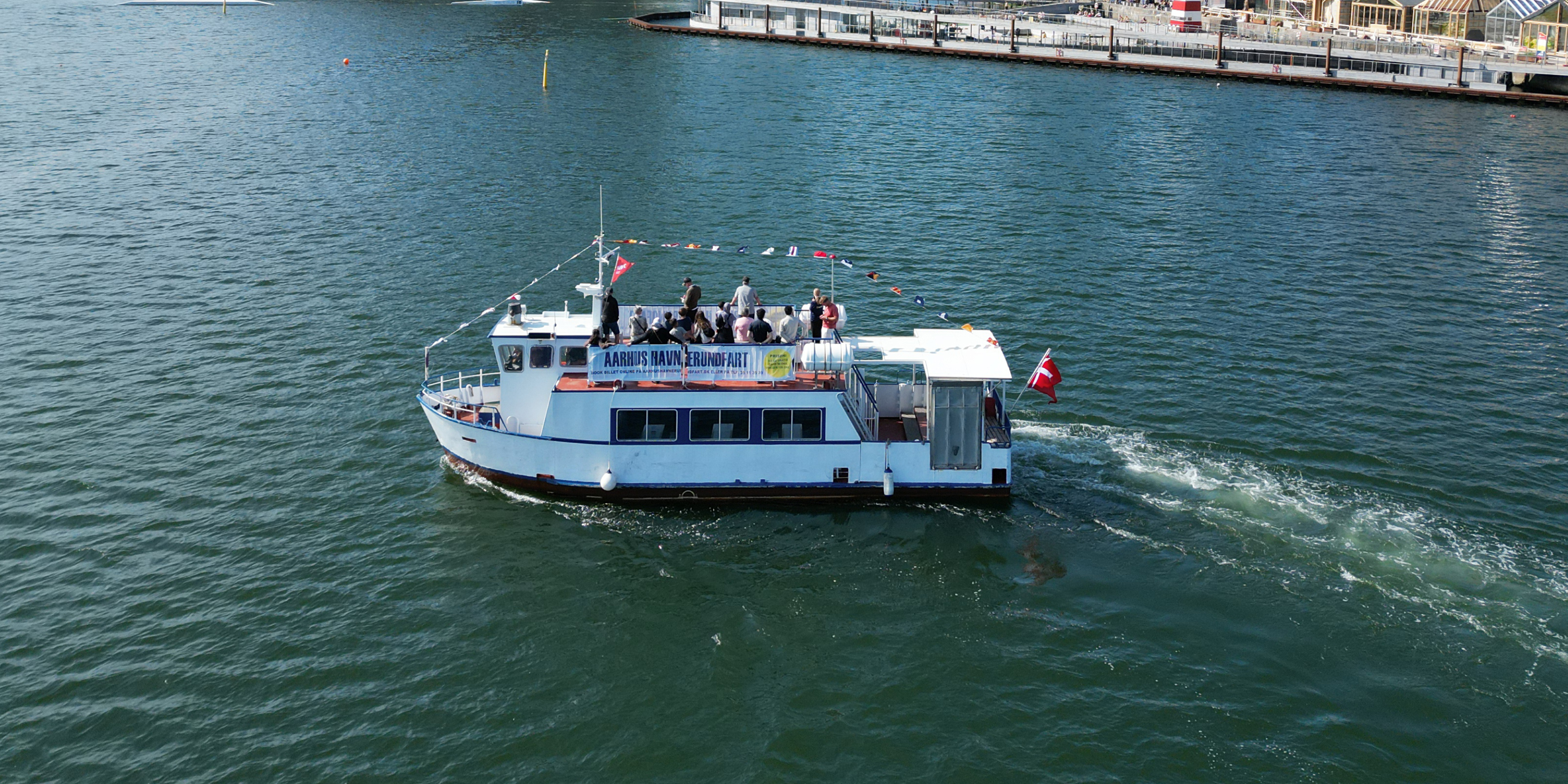 Aarhus Havn Rundfart båd sejler nær kajen med passagerer om bord i Aarhus Havn i fugleperspektiv.