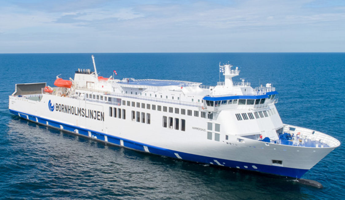 Bornholmslinjen ses fra venstre i fugleperspektiv omkranset af det blå hav og en lyseblå himmel.