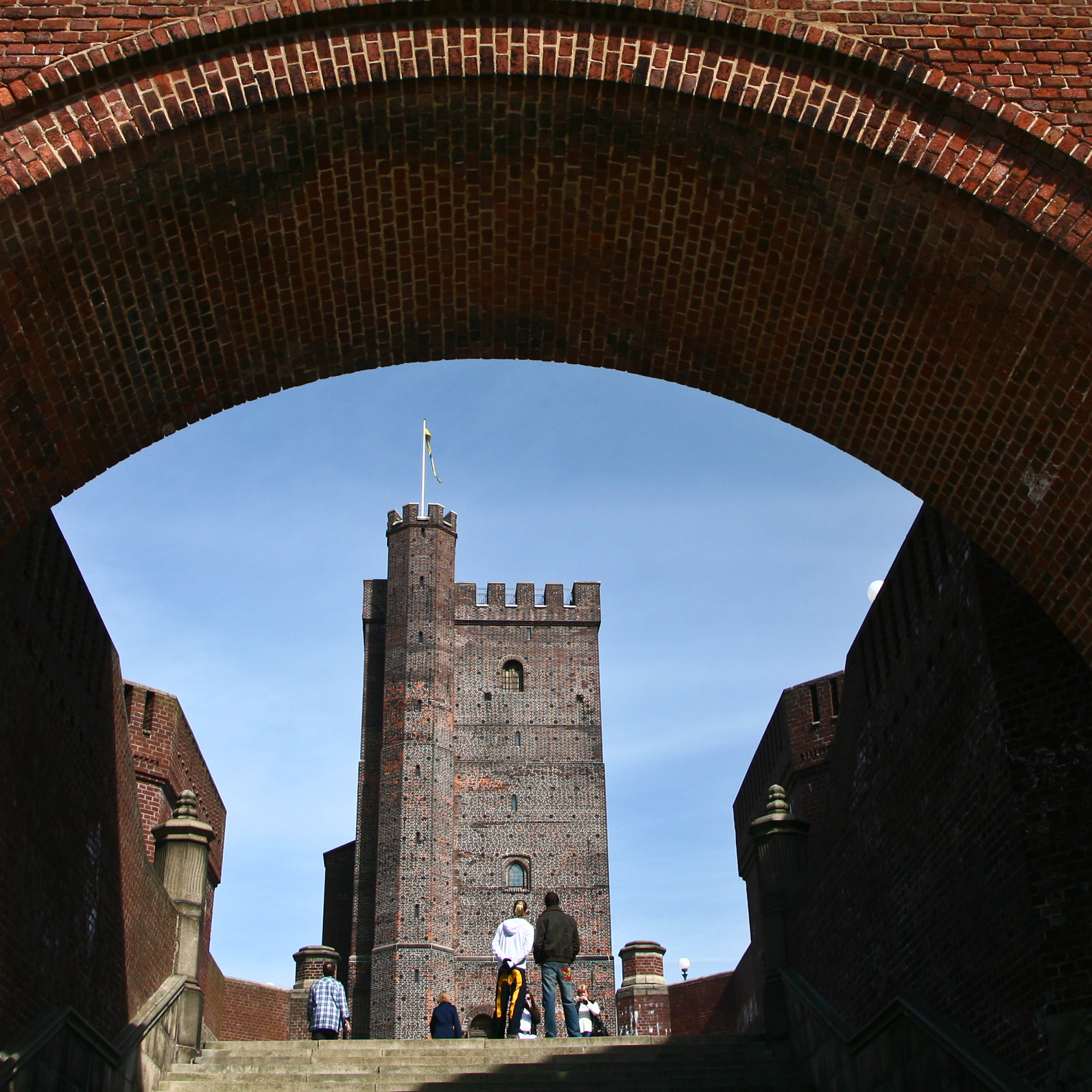 Kronborg Slot set fra en murstensbue med himlen som baggrund.