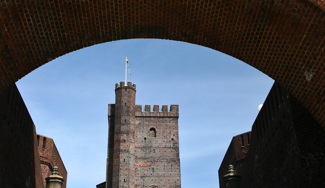 Kronborg Slot set fra en murstensbue med himlen som baggrund.