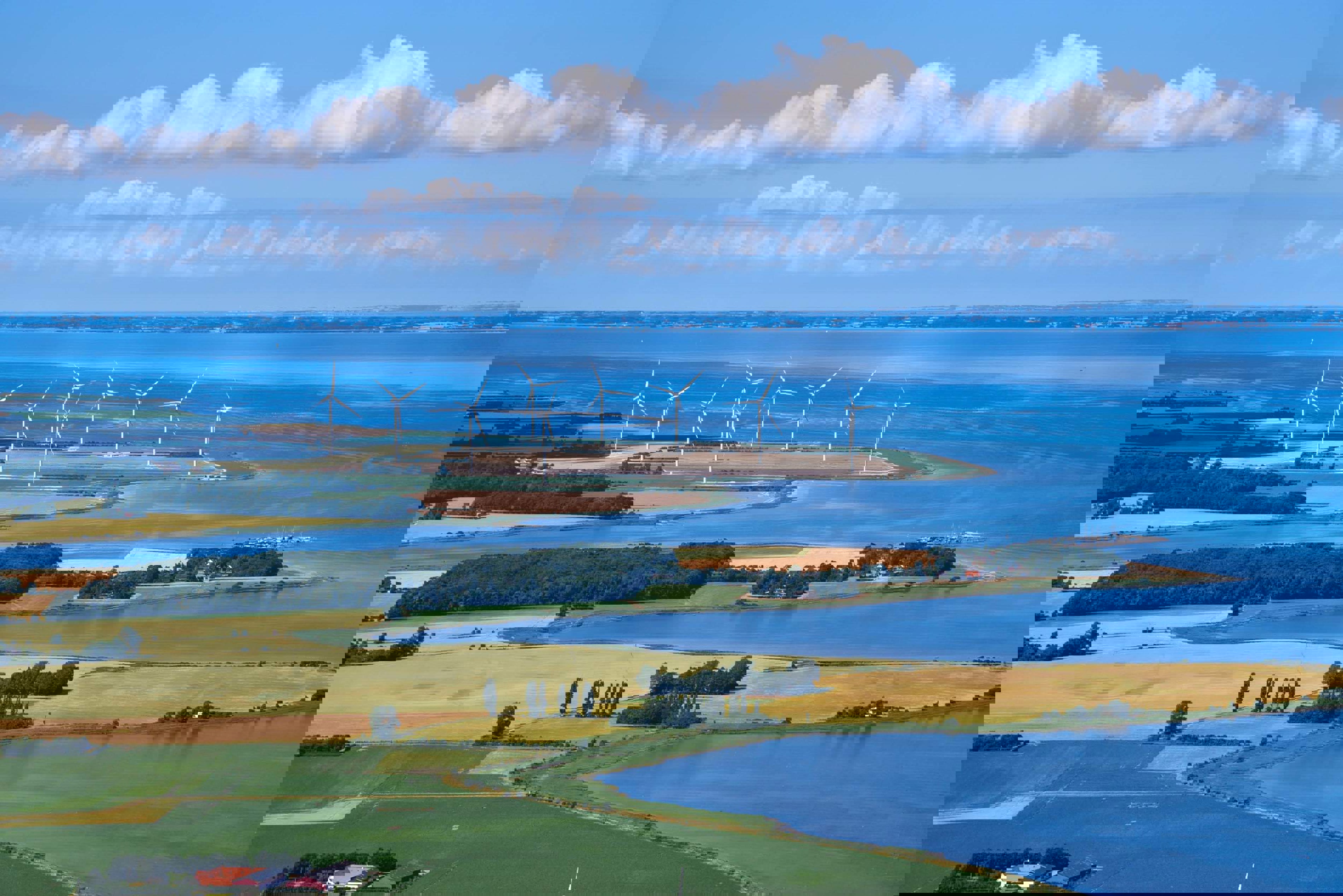 Langeland aus der Vogelperspektive mit Windmühlen am Horizont und grünen Feldern.