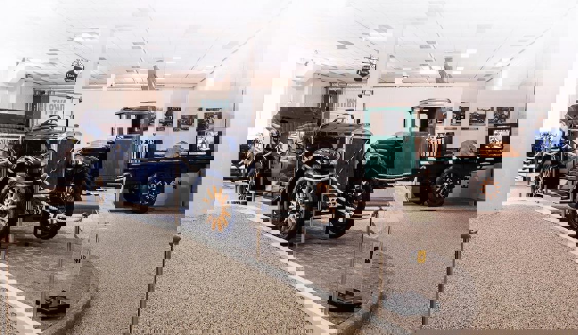 Indendørs ses flere gamle biler parkeret med museumsbånd omkring.