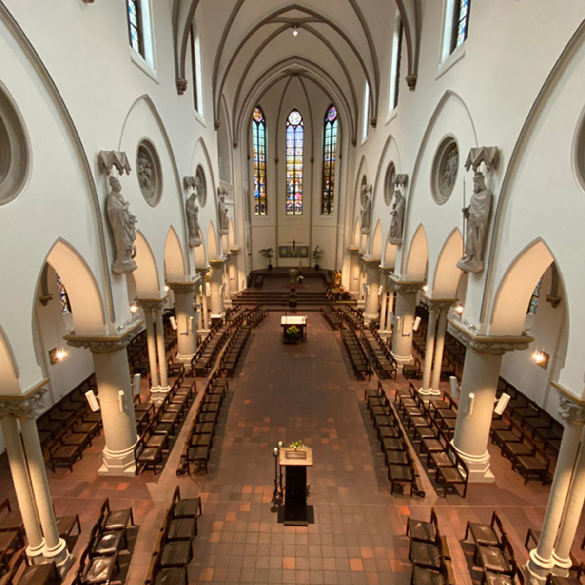 Indvendig udsigt over en gotisk katedral, med buede lofter, søjler og farverige glasvinduer, set fra oven.