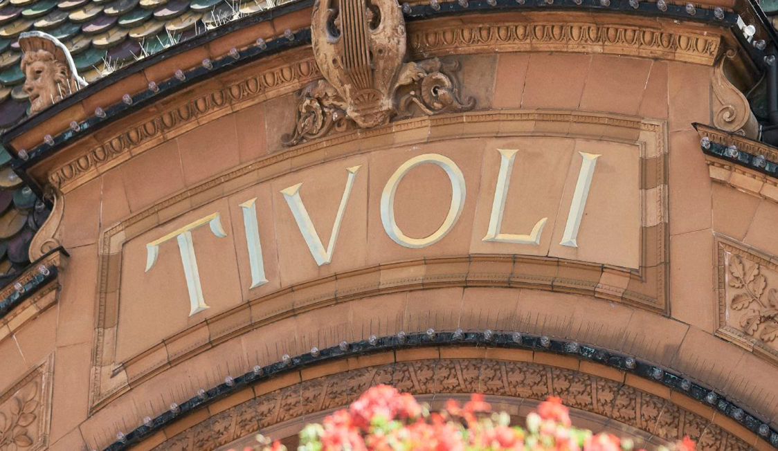 Ingången till Tivoli i Köpenhamn med dekorativa detaljer och tydlig skyltning av nöjesparkens namn.