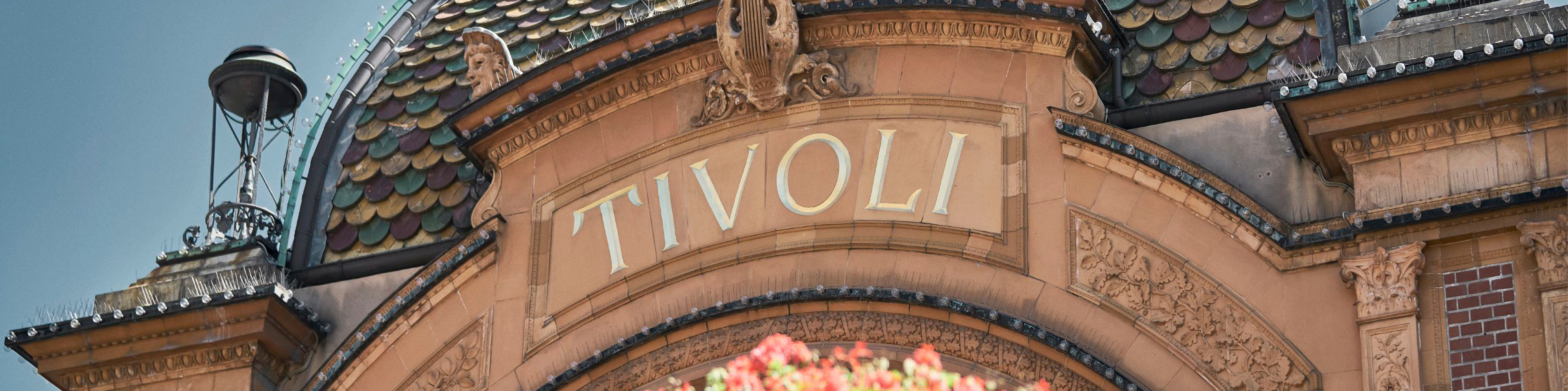 Ingången till Tivoli i Köpenhamn med dekorativa detaljer och tydlig skyltning av nöjesparkens namn.