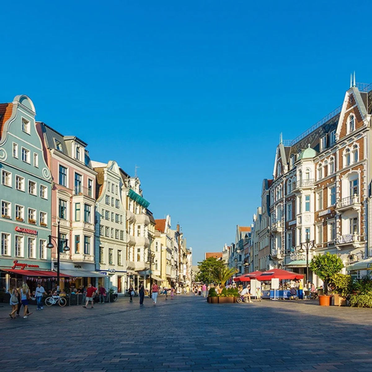 Shoppingstråket i centrala Rostock med historiska byggnader och gående människor en solig dag.