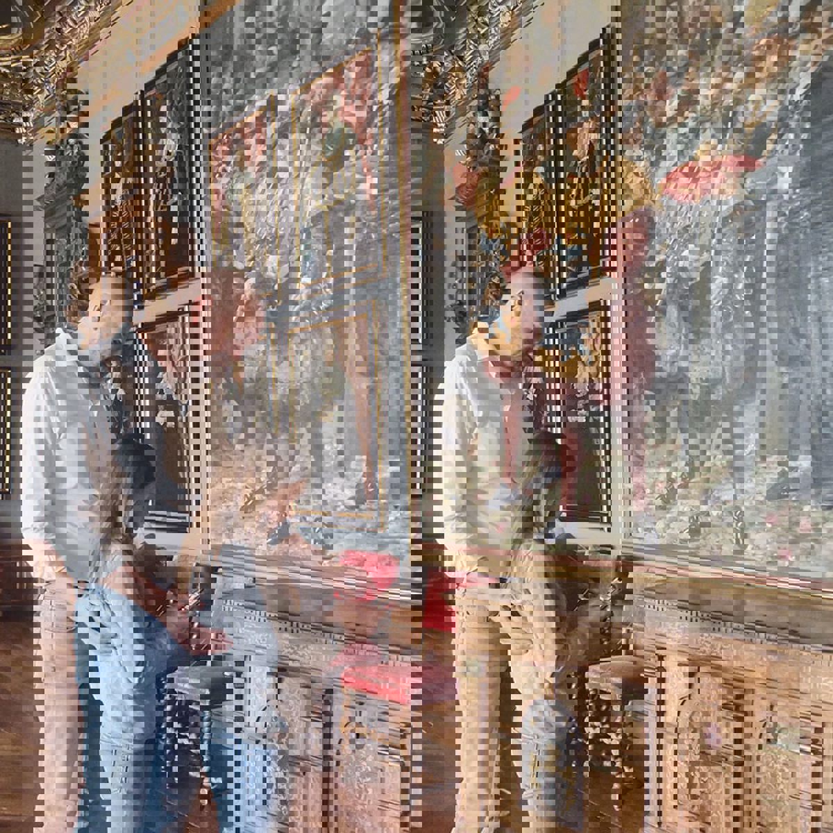 Far och dotter tittar på telefonen inne på Frederiksborgs slott framför en målning.