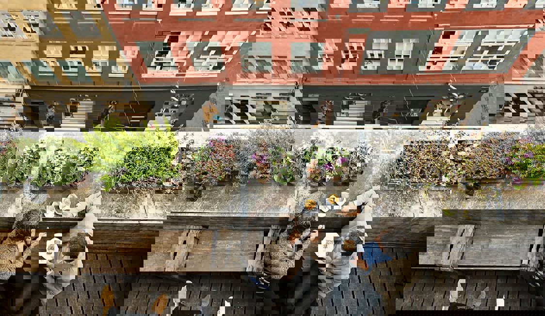 I ett fågelperspektiv ser man ett par som äter och dricker på toppen av en byggnad med utsikt över gatan.
