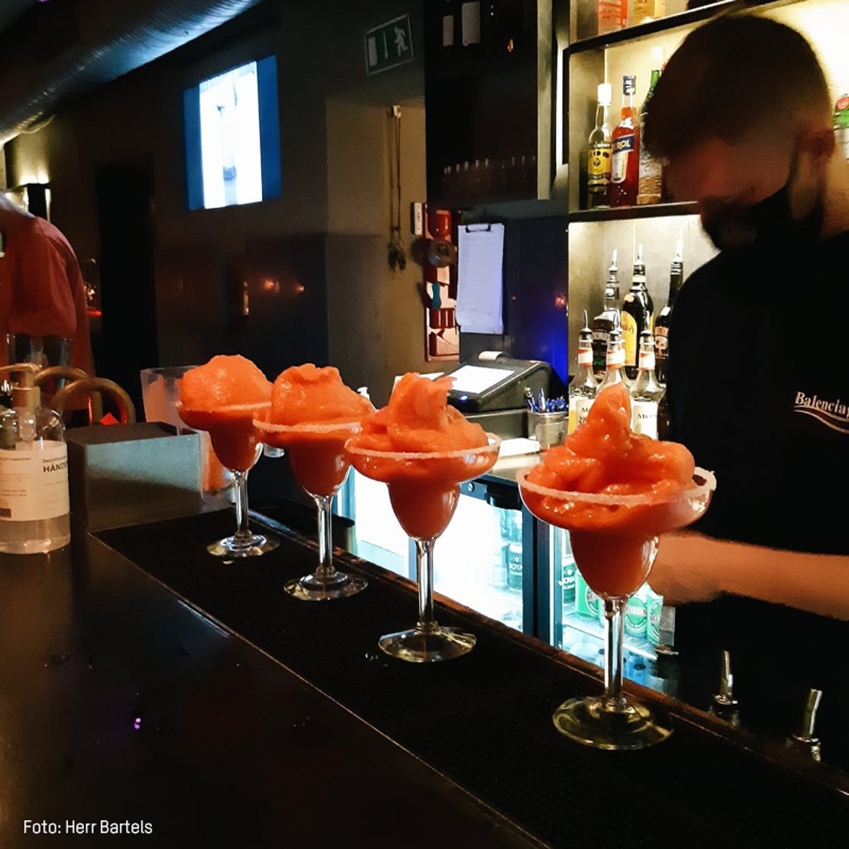 Fem jordbær margaritaer på en bar diskret belyst i en trendy cocktailbar.
