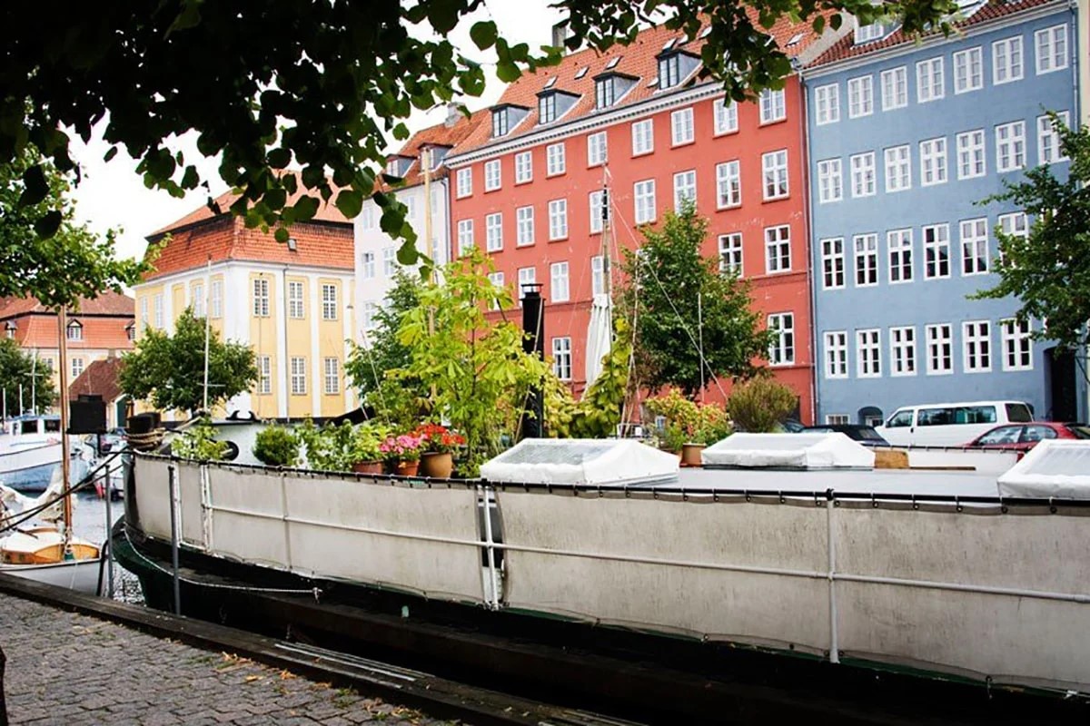 Kristianshavn husbåt vid färgglada byggnader och kanaler i Köpenhamn med gröna växter ombord.