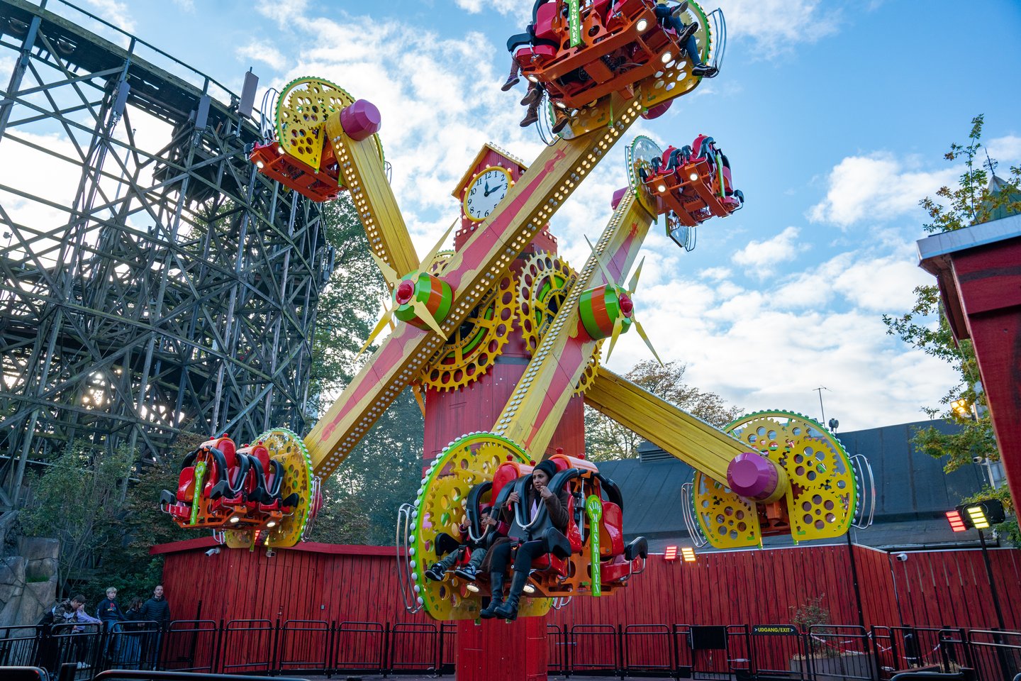 Farverigt karussel i forlystelsespark svinger gæster op i luften under en klar blå himmel.