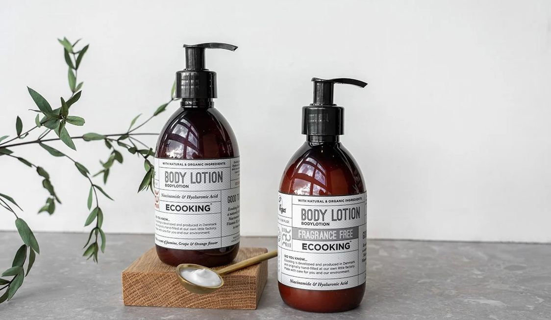 Økologisk bodylotion fra Ecooking med hyaluronsyre, to brun flasker med pumpe i minimalistisk miljø.