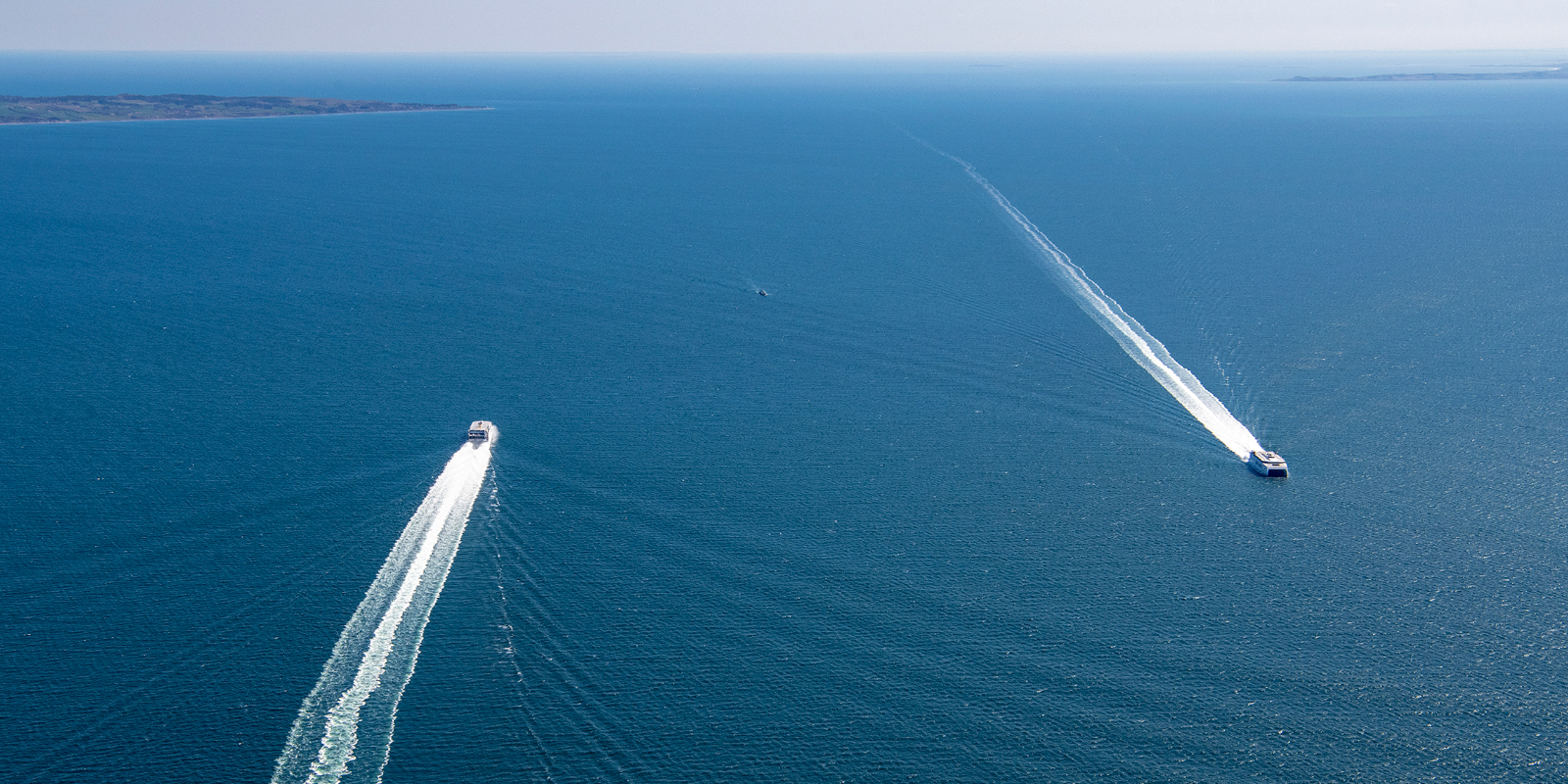 Two Molslinjen ferries sailing parallel on the open sea, viewed from an aerial view.