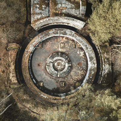 Luftfoto af cirkulær bunker omringet af skov, set oppefra i vinterlandskab